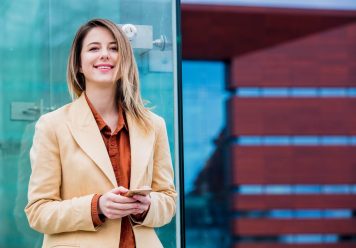 businesswoman-typing-message-by-phone-on-the-city-2022-01-12-05-06-15-utc